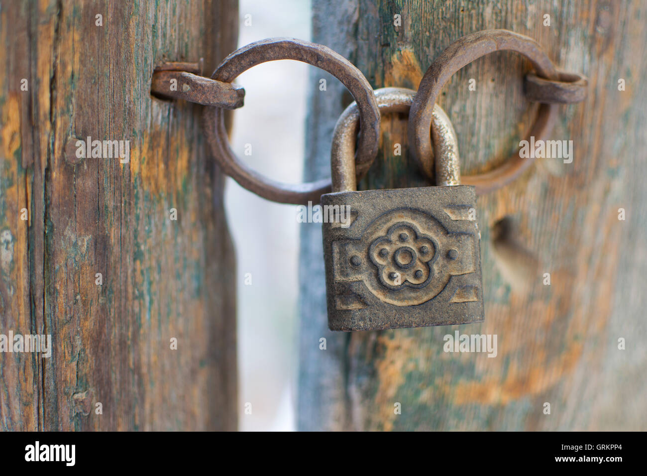 Vecchio arrugginito lucchetto decorato su una porta di legno. Vintage lucchetto corrosi su un antico cancello dello sfondo. Foto Stock