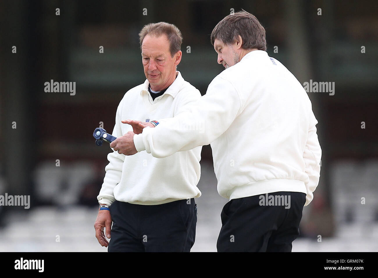 Di arbitri Pietro Willey (R) e Jeremy Lloyds considerare il misuratore di luce lettura in anticipo di gioco sul Giorno 3 - Surrey CCC vs Essex CCC - LV County Championship Division due Cricket alla Kia ovale, Kennington, Londra - 22/04/14 Foto Stock