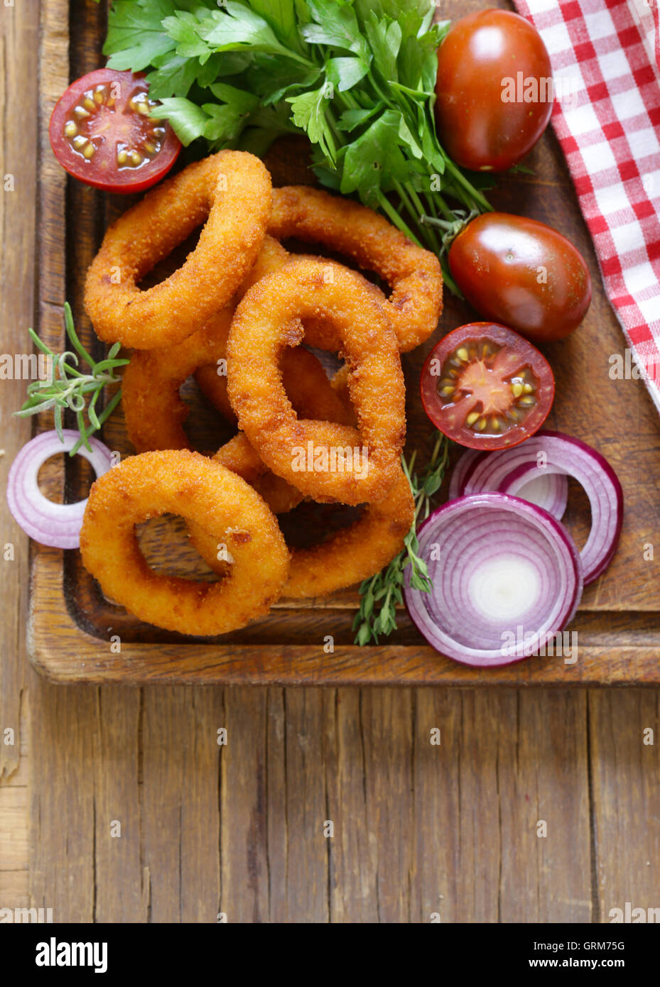 Anelli di cipolla fritti su un tavolo di legno, fast food Foto Stock