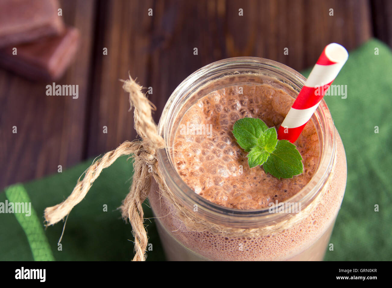 Frullato al cioccolato (frullato) con la menta e paglia in barattolo scuro sul tavolo di legno Foto Stock