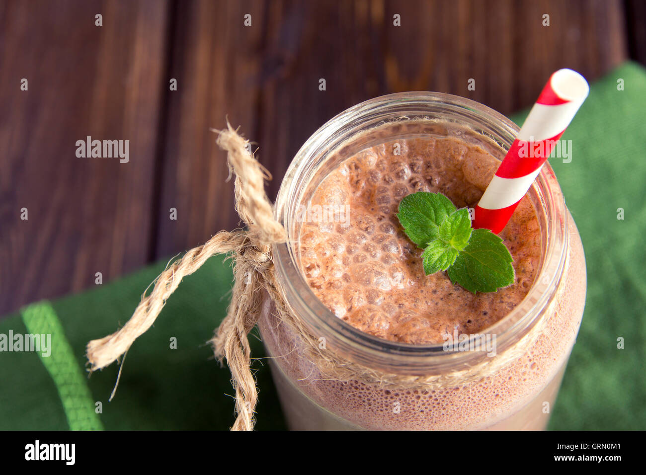 Frullato al cioccolato (frullato) con la menta e paglia in barattolo scuro sul tavolo di legno Foto Stock