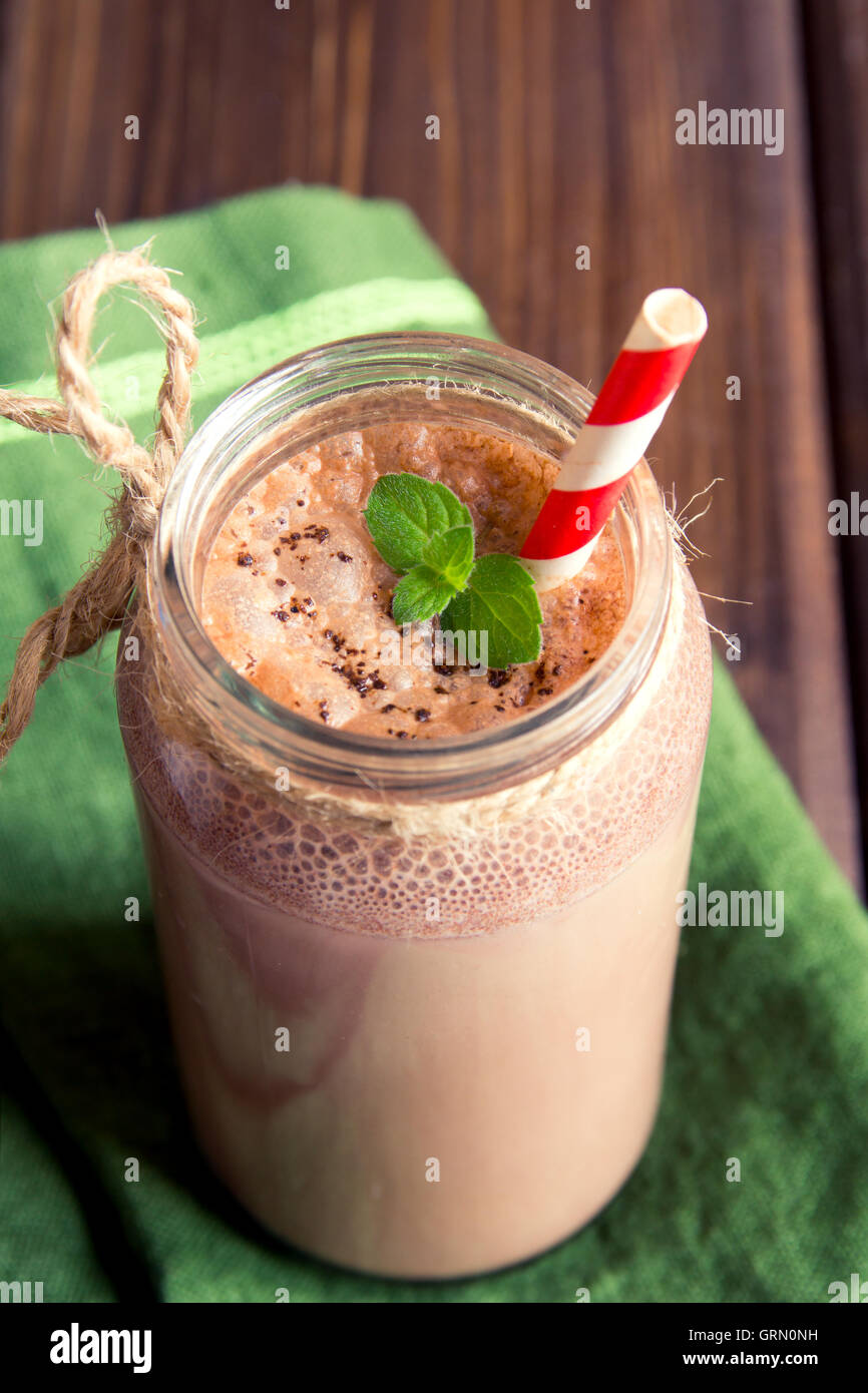 Frullato al cioccolato (frullato) con la menta e paglia in barattolo scuro sul tavolo di legno Foto Stock