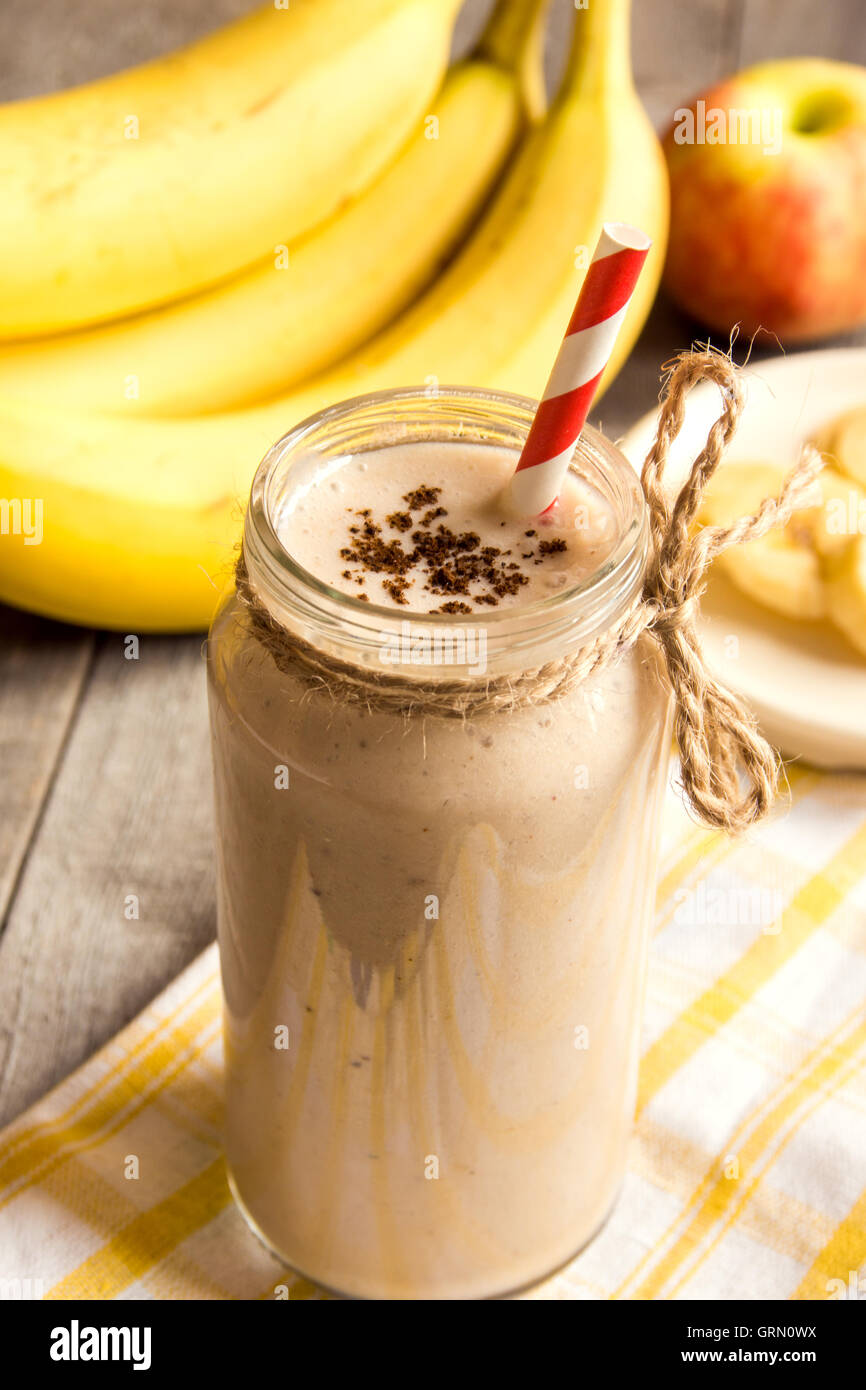 Frullato di frutta (banana, mela, pesca) con cannella su sfondo di legno Foto Stock