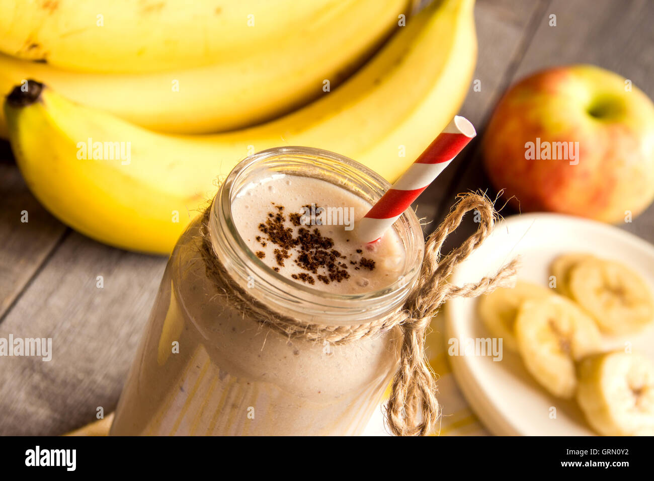 Frullato di frutta (banana, mela, pesca) con cannella su sfondo di legno Foto Stock