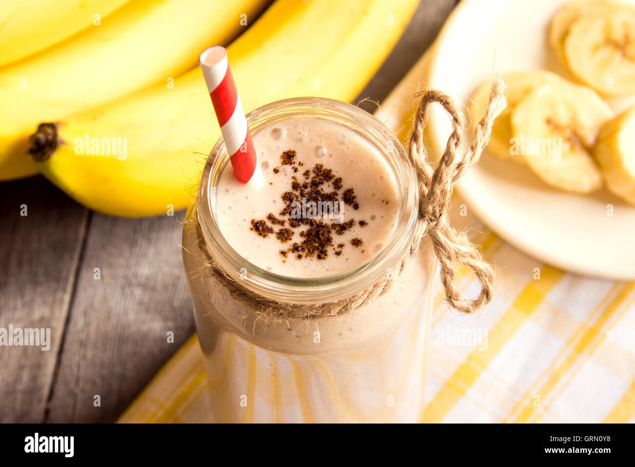 Frullato di banana con cannella su sfondo di legno Foto Stock