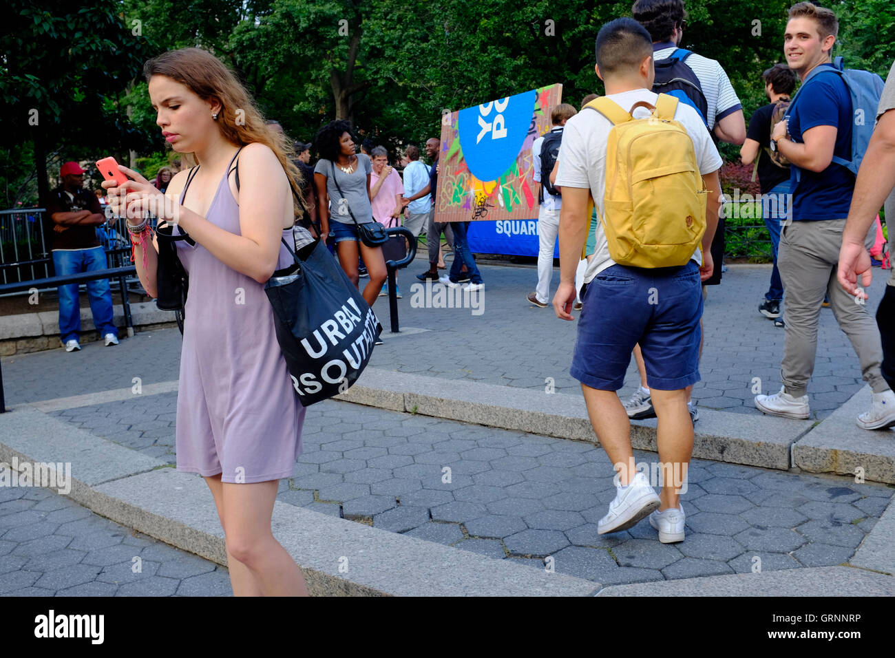 Una giovane donna texting sul suo cellulare quando lei sta camminando in Union Square park,Manhattan,New York City,USA Foto Stock