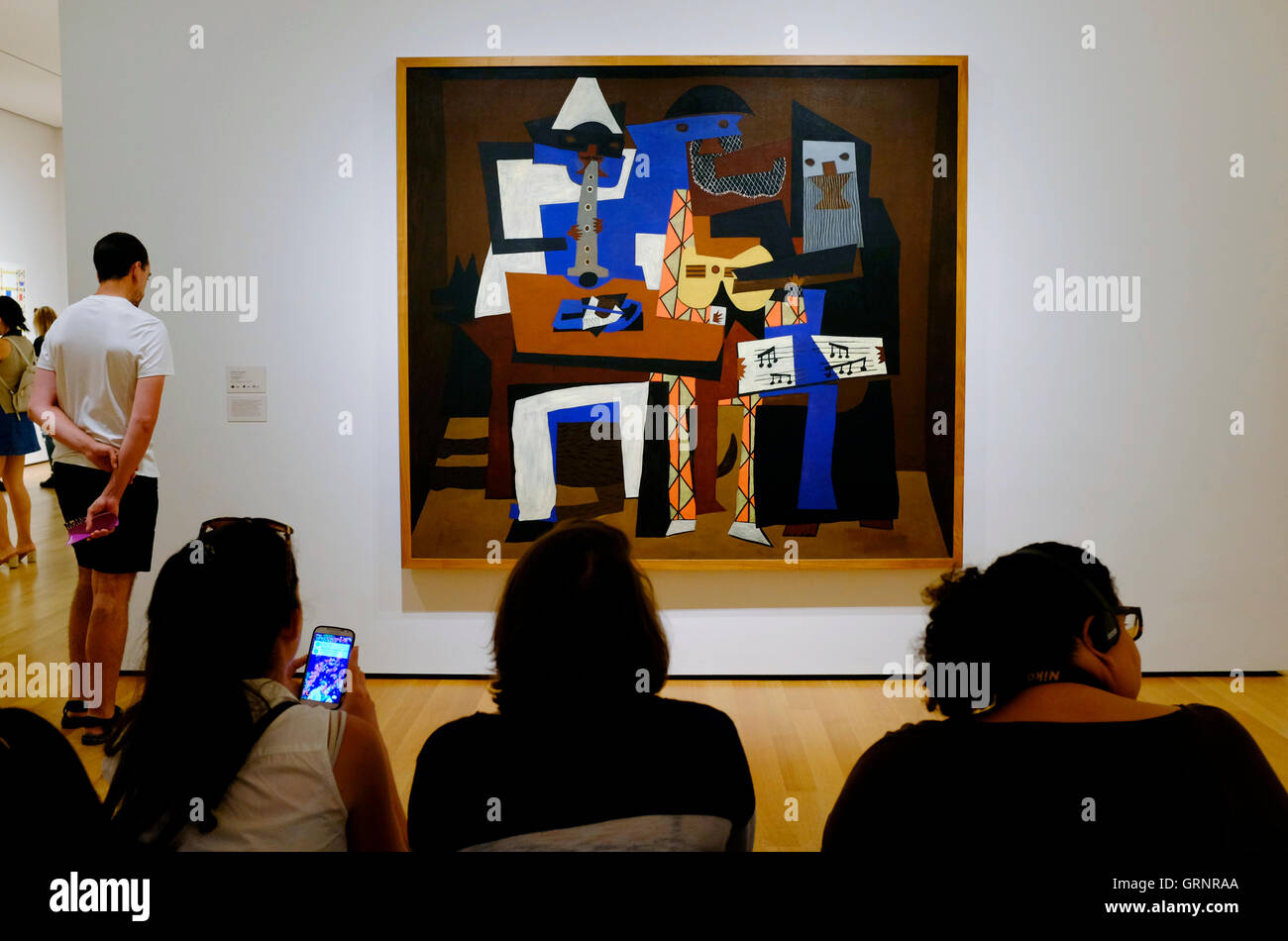 I visitatori di fronte di Pablo Picasso tre musicisti nel Museo di Arte Moderna MoMA aka. New York City.USA Foto Stock