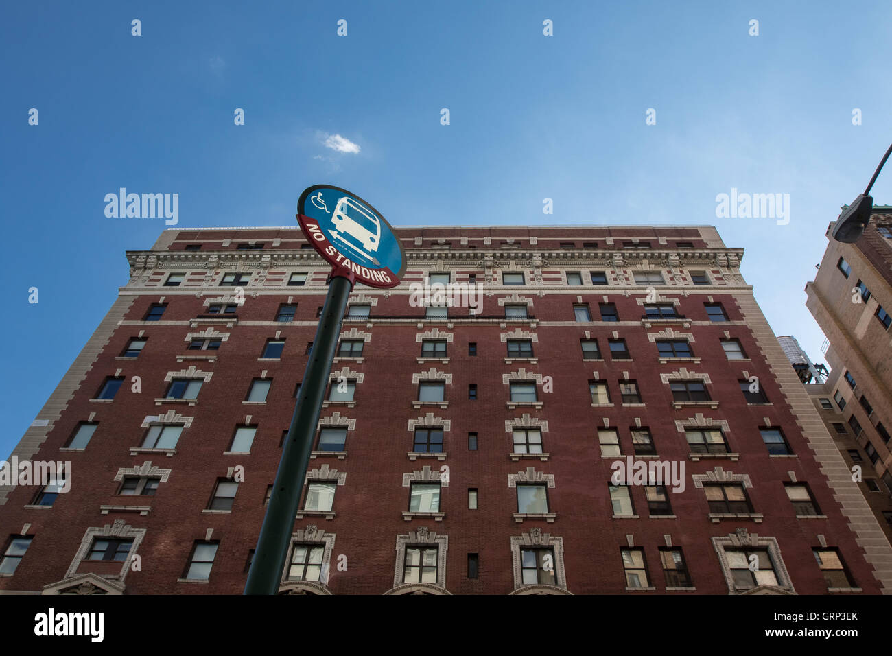 Una fermata pole contro un edifici residenziali e cielo blu. Foto Stock