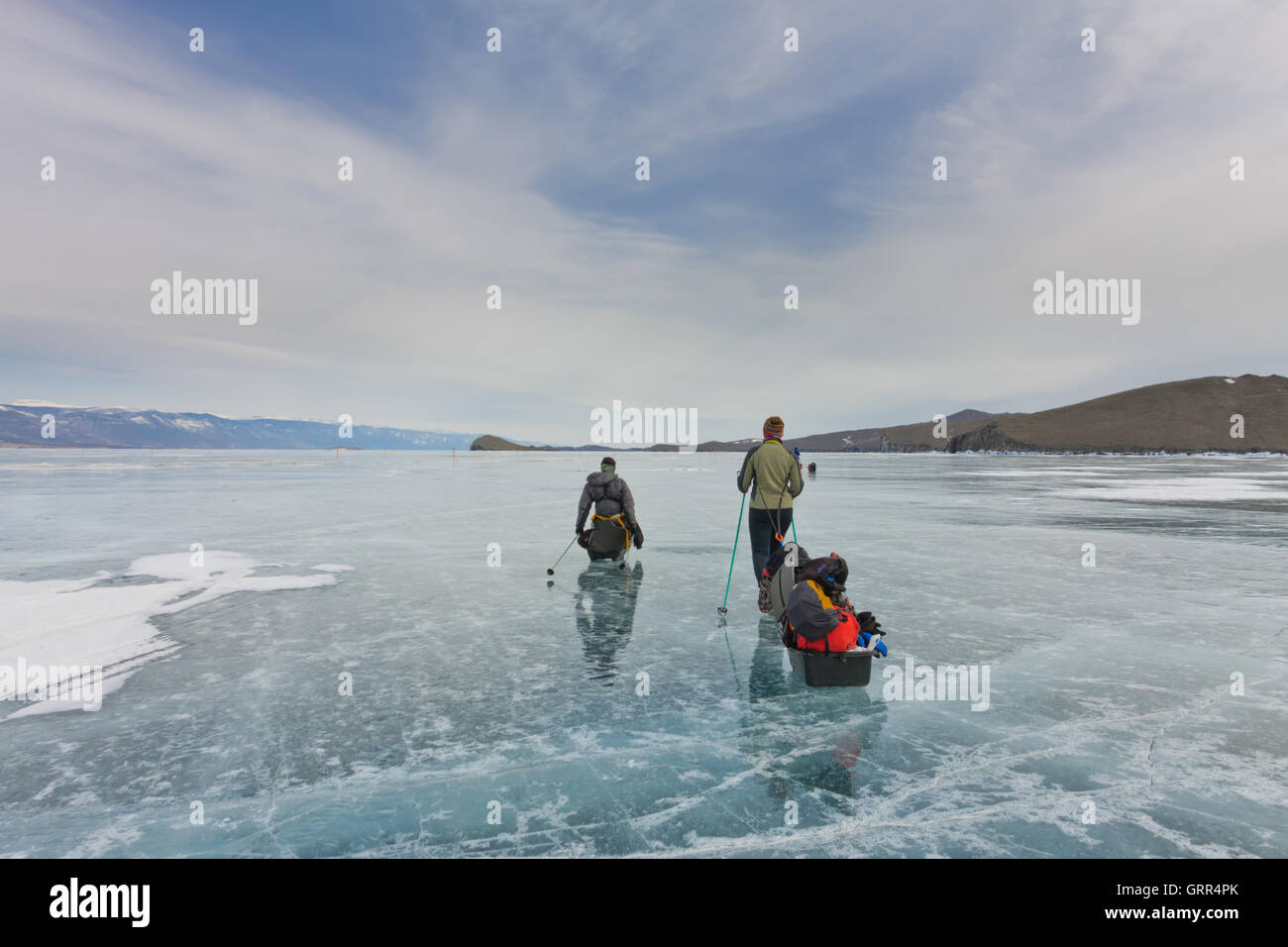 Una donna e un uomo con una mazza e trekking pole è sull'azzurro ghiaccio del Baikal Foto Stock