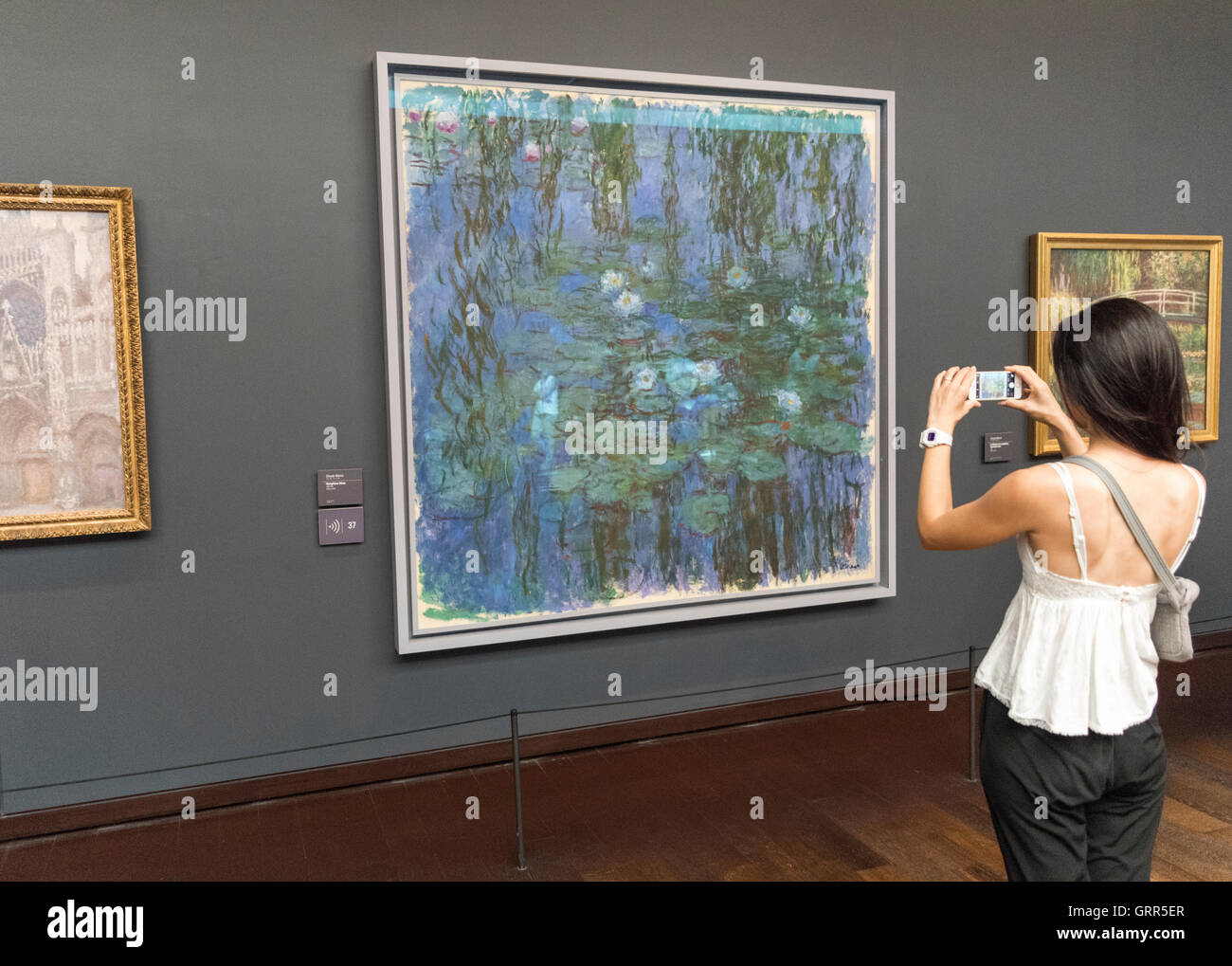 Turistica prendendo le foto sull'iPhone di Nympheas bleus di Claude Monet al Musée d'Orsay Museum, Parigi, Francia Foto Stock