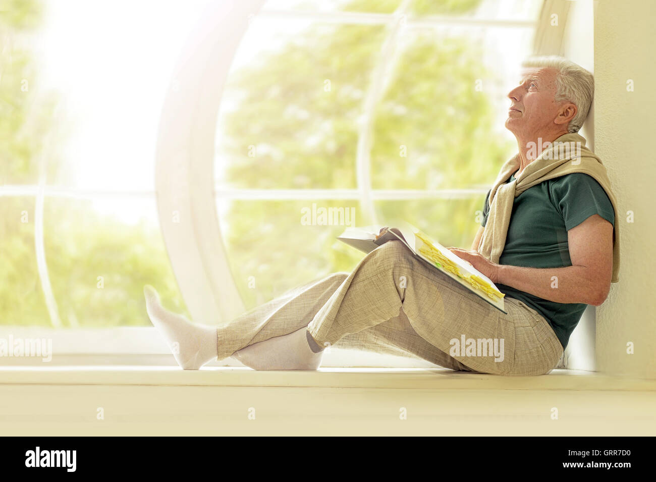 L'uomo anziano con il libro a casa tua Foto Stock