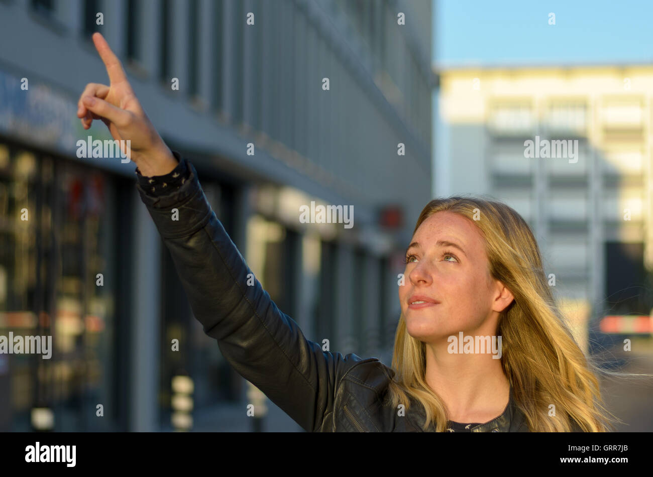 Piuttosto giovane donna rivolto verso l'alto in città verso l'esterno di un edificio commerciale nella luce della sera Foto Stock
