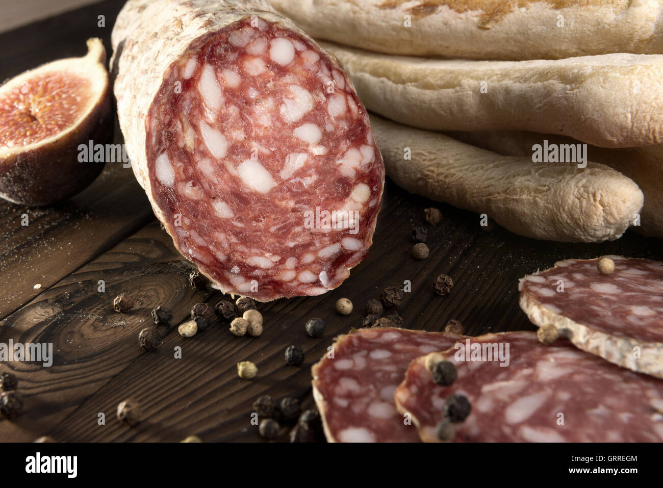 Secco italiano-cured salsiccia e grissino - grissino su uno sfondo di legno Foto Stock