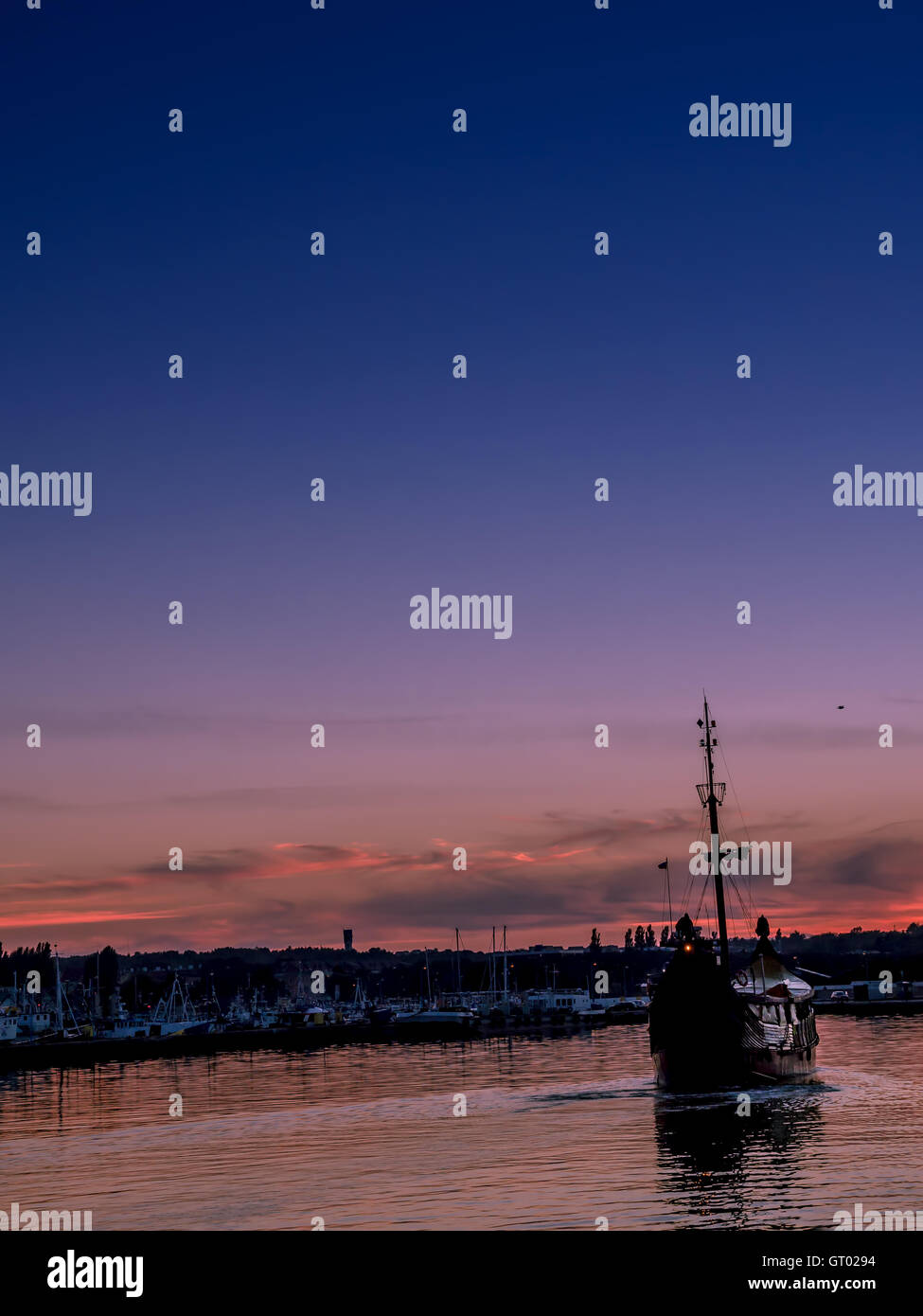 Storica vecchia nave a vela di entrare nella marina contro il cielo al tramonto Foto Stock