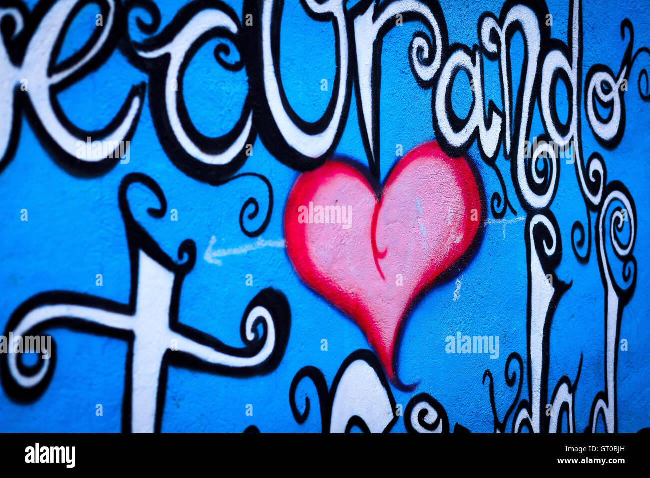 Cuore di graffiti su una parete blu con strisce bianche e disegni Foto Stock