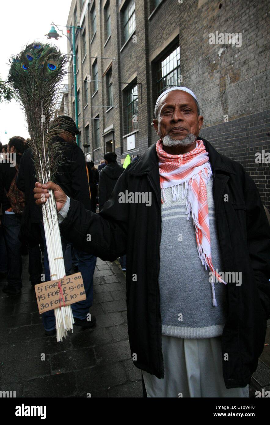 Uomo in bengali la vendita di penne di pavone, Brick Lane, London, Regno Unito Foto Stock