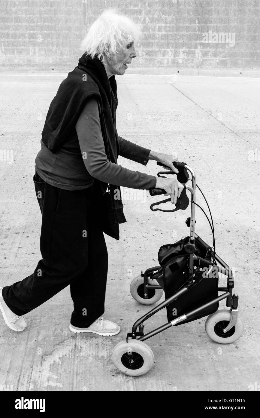 Una donna anziana a piedi con una camminata Rollator Aiuto, Rottingdean, Sussex, Regno Unito Foto Stock