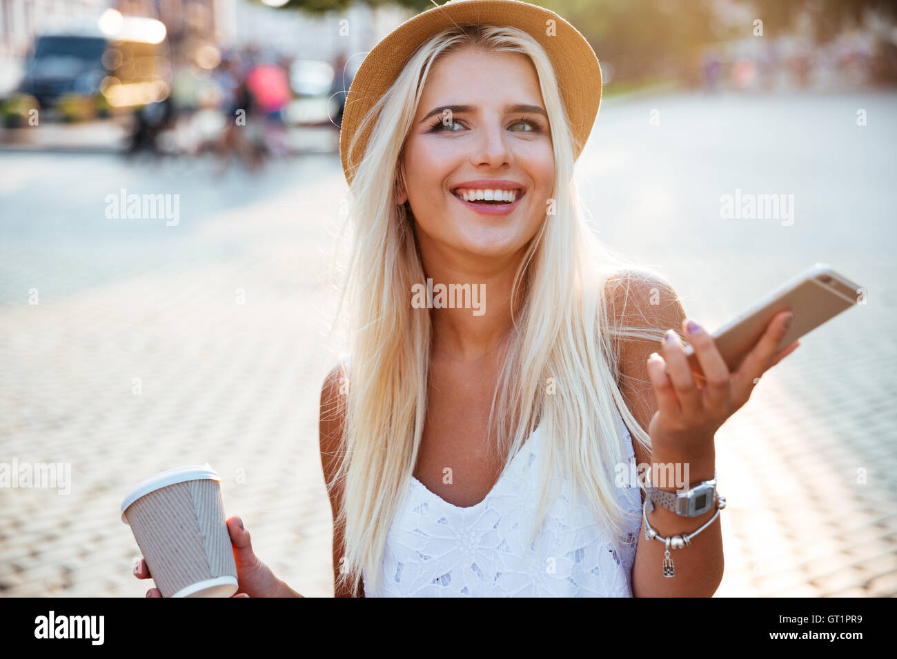 Close up ritratto di una ragazza in hat holding take away tazza da caffè e lo smartphone Foto Stock