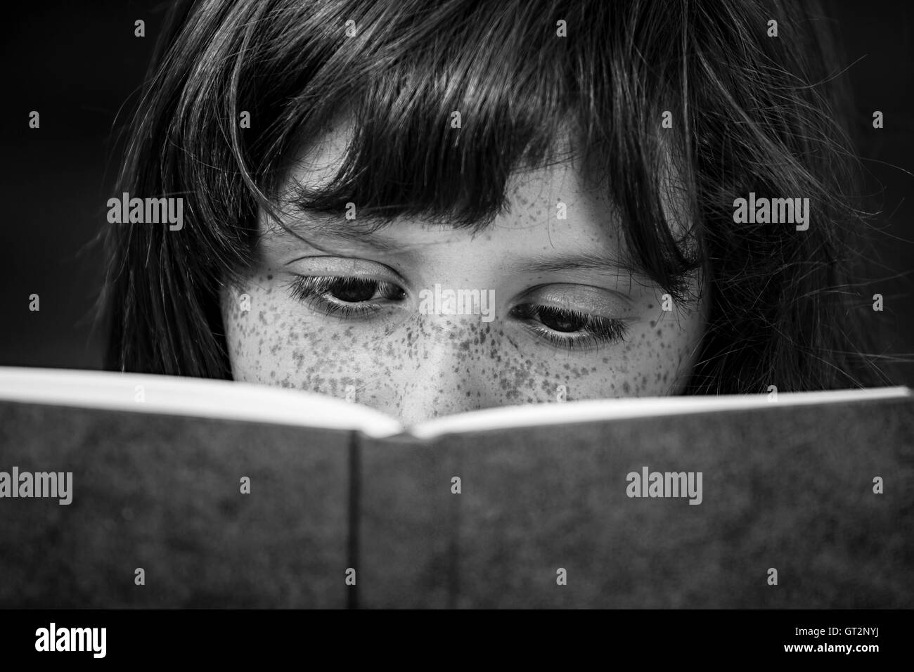 La scolaretta leggendo un libro all'aperto Foto Stock