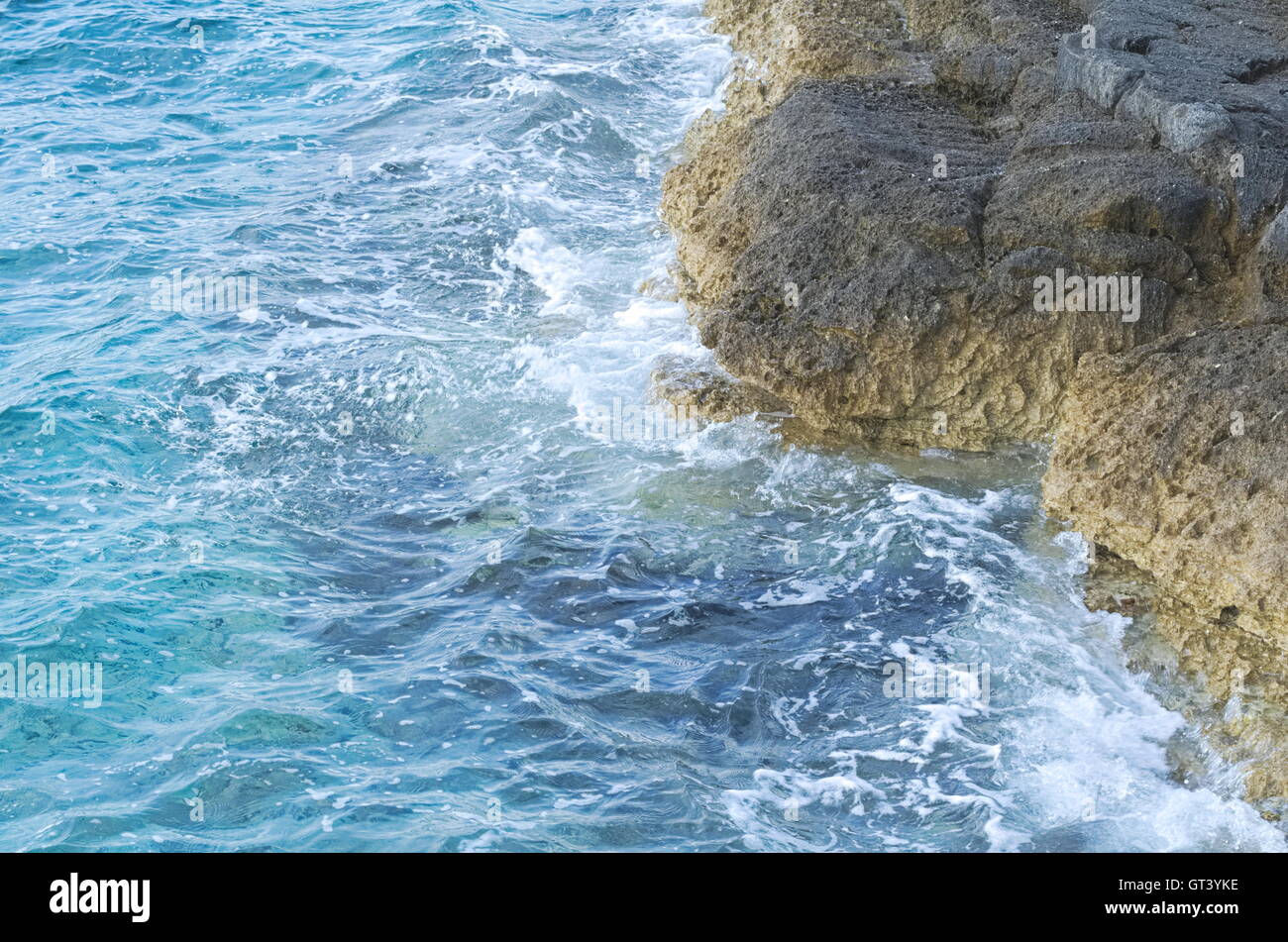 Ondulata blu mare e spiaggia rocciosa Closeup Foto Stock
