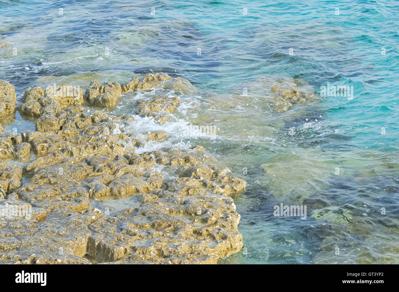 Ondulata blu mare e spiaggia rocciosa Closeup Foto Stock