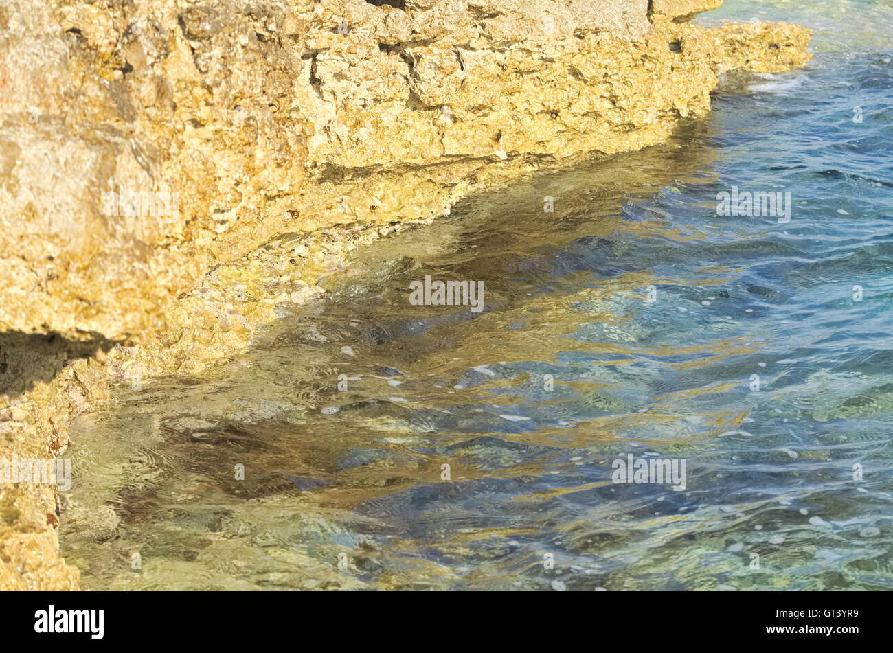 Mare ondeggiante color oro e Costa Rocciosa Closeup Foto Stock