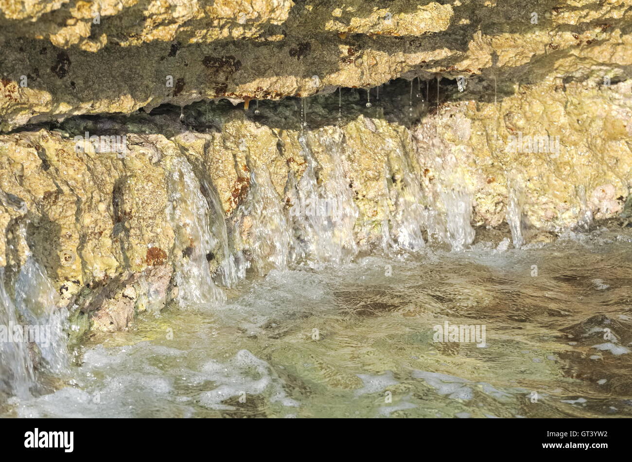 Mare ondeggiante color oro e Costa Rocciosa Closeup Foto Stock
