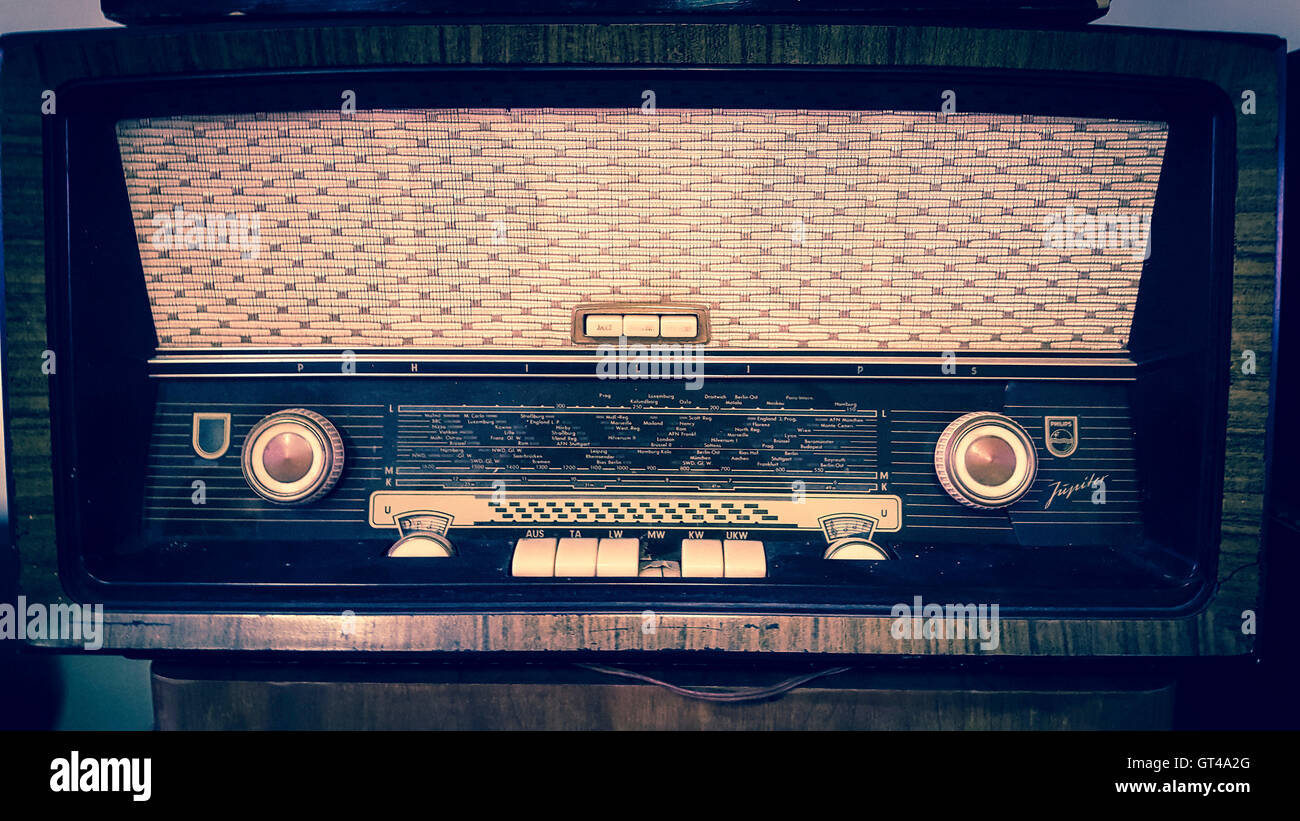 Radio d'epoca esposta su uno scaffale in legno in un accogliente soggiorno con illuminazione calda e arredi nostalgici Foto Stock