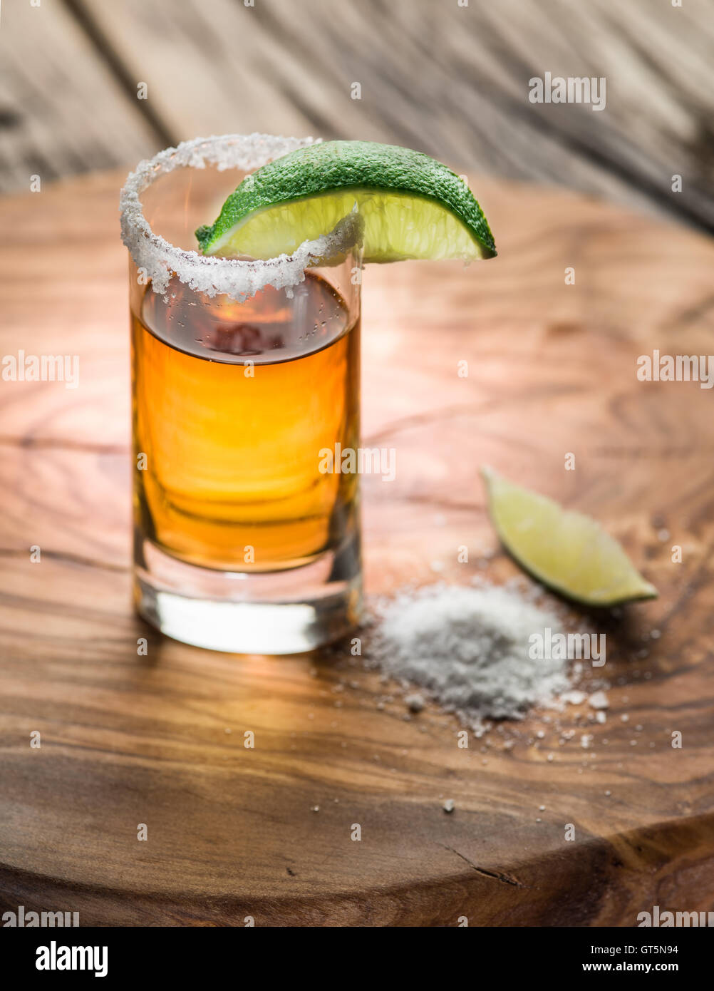 Single shot di tequila serviti con calce e sale sullo sfondo di legno. Foto Stock