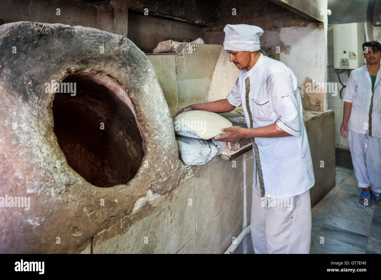 Un panettiere utilizza un forno tandoori per cuocere fresche pane taftoon  in Yazd, Iran Foto stock - Alamy