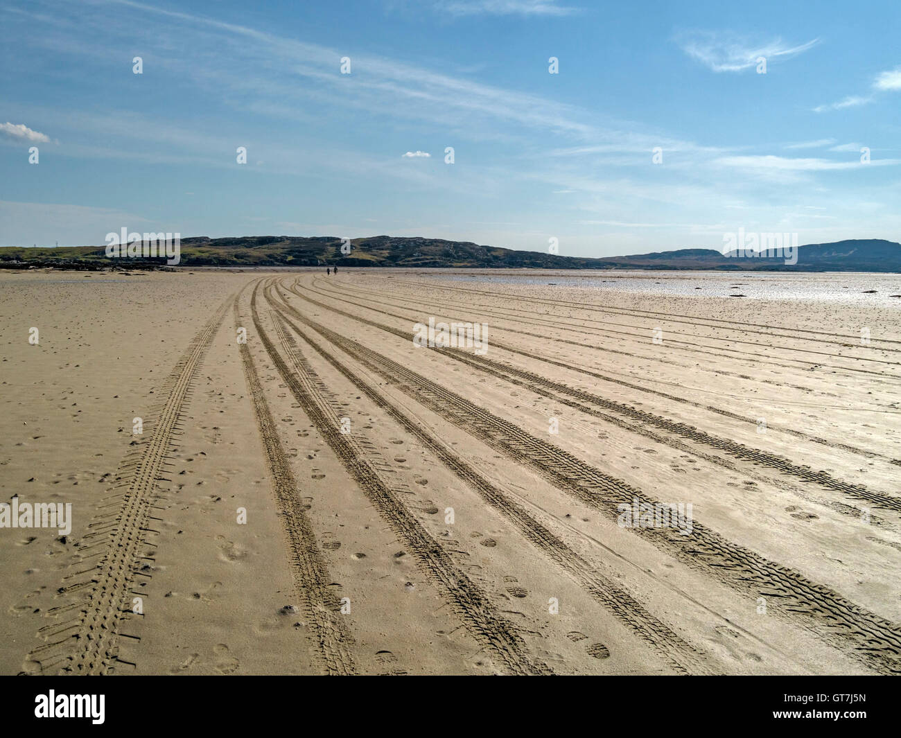 Tracce di pneumatici nella sabbia che conduce all'isola di marea di Oronsay e giovane tornando, Strand Isola di Colonsay, Scotland, Regno Unito. Foto Stock