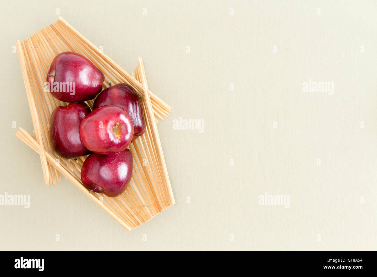 Sani e freschi Mele rosse su un vassoio in legno posto sulla sommità di un verde chiaro Tavolo, sottolineando la copia dello spazio. Catturate in un angolo alto V Foto Stock