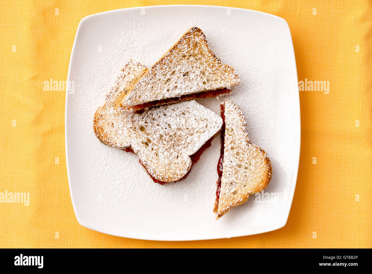 Vista aerea del toast alla francese un pane dolce con confettura di fragole riempimento sulla piastra bianca per la prima colazione. Isolato su Backg giallo Foto Stock