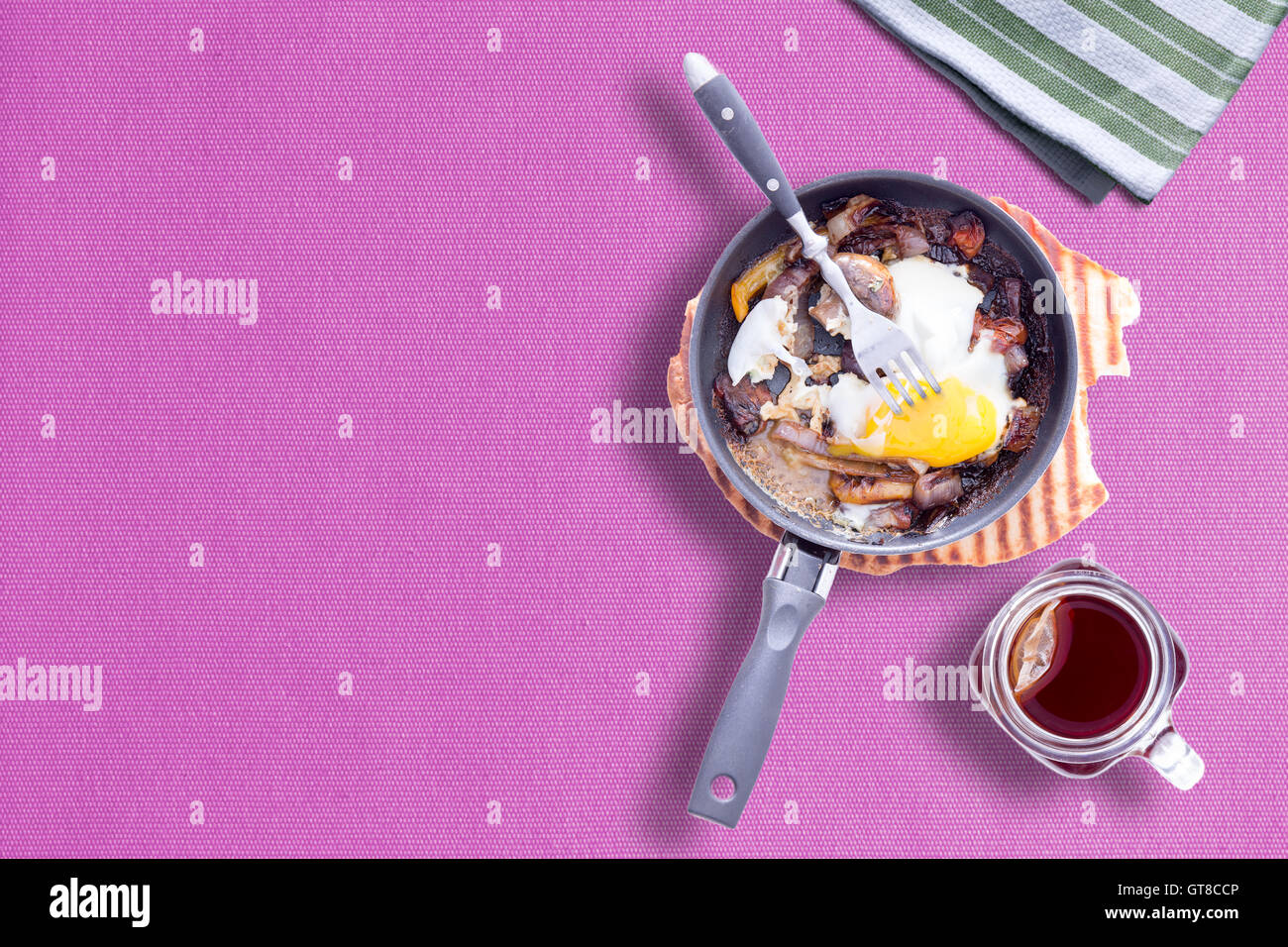 Sunny Side fino la frittata sul colore viola tabella panno con un muratore tazza di tè caldo, copia spazio a sinistra a sinistra Foto Stock