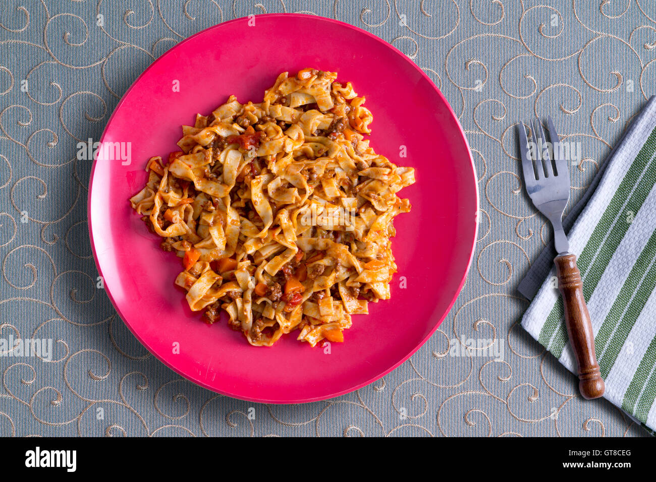 Piastra della deliziosa casa fettuccine con un saporito pomodoro e salsa di erbe servita su un decorativo tovaglia whorled, vista Foto Stock