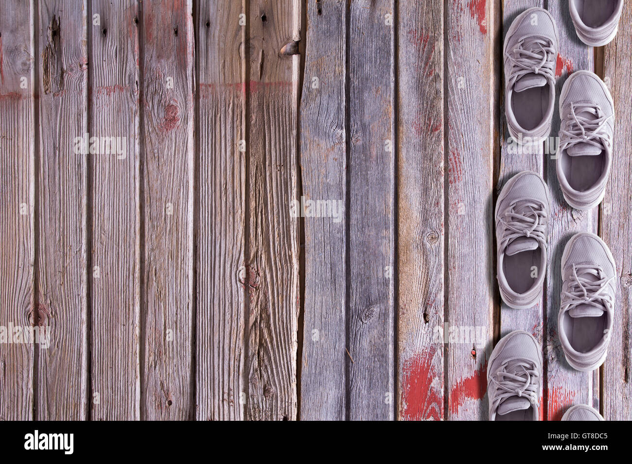 Calzatura confine con una doppia fila di formatori usurati o sneakers disposti come se camminando su una texture di sfondo di legno duro del vecchio f Foto Stock