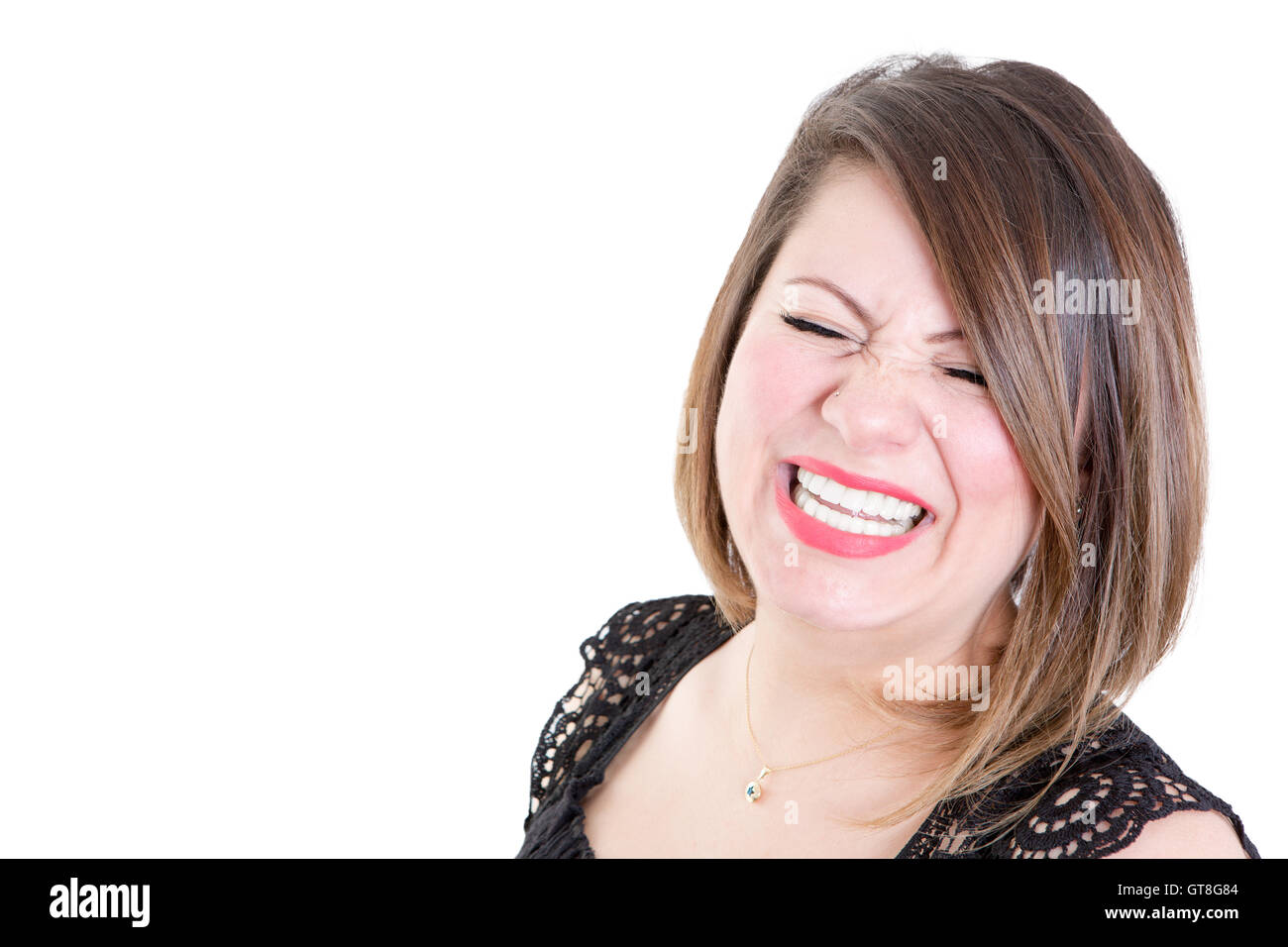 Close up Molto donna felice che mostra un sorriso toothy con gli occhi chiusi contro uno sfondo bianco con copia spazio sulla sinistra. Foto Stock