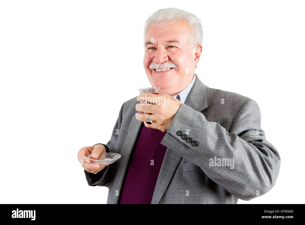Mezzo Corpo colpo di un sorridente di mezza età imprenditore, tenendo un tè turco mentre guardando fuori contro uno sfondo bianco. Foto Stock