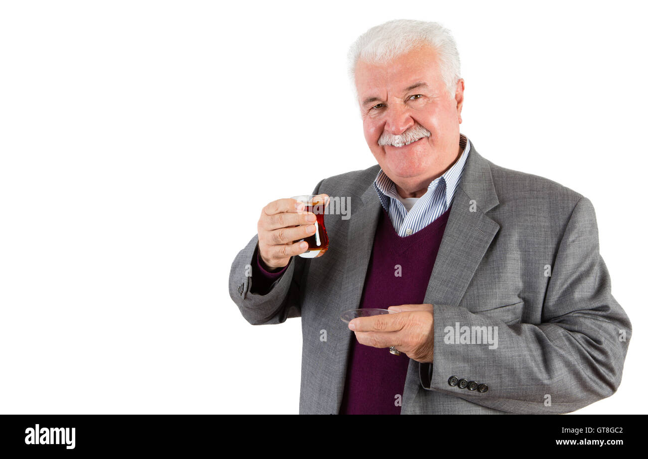 Mezzo Corpo colpo di un imprenditore Senior tenendo un bicchiere di tè turco e sorridente alla fotocamera contro uno sfondo bianco. Foto Stock