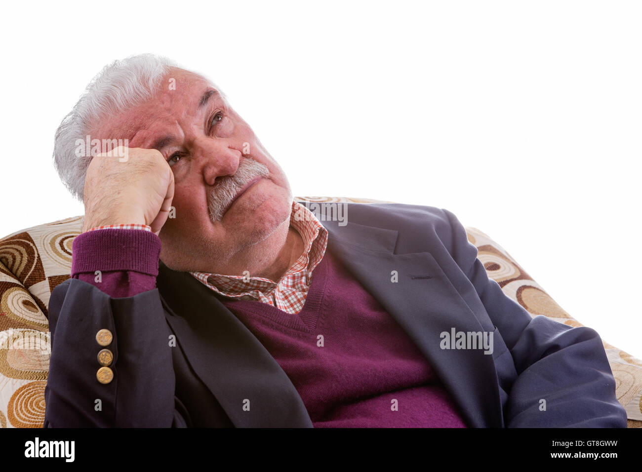 Anziani pensionati uomo rilassante in un confortevole poltrona fissando attentamente fino in aria con un intento di espressione, isolato Foto Stock