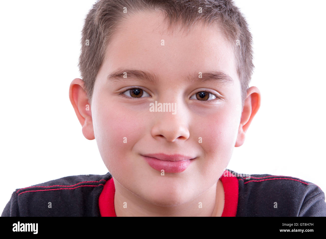 Testa e spalle Close Up Ritratto di giovane ragazzo che indossa il rosso e il nero di T-Shirt e fissando con soddisfazione alla fotocamera con timido sorridenti Foto Stock