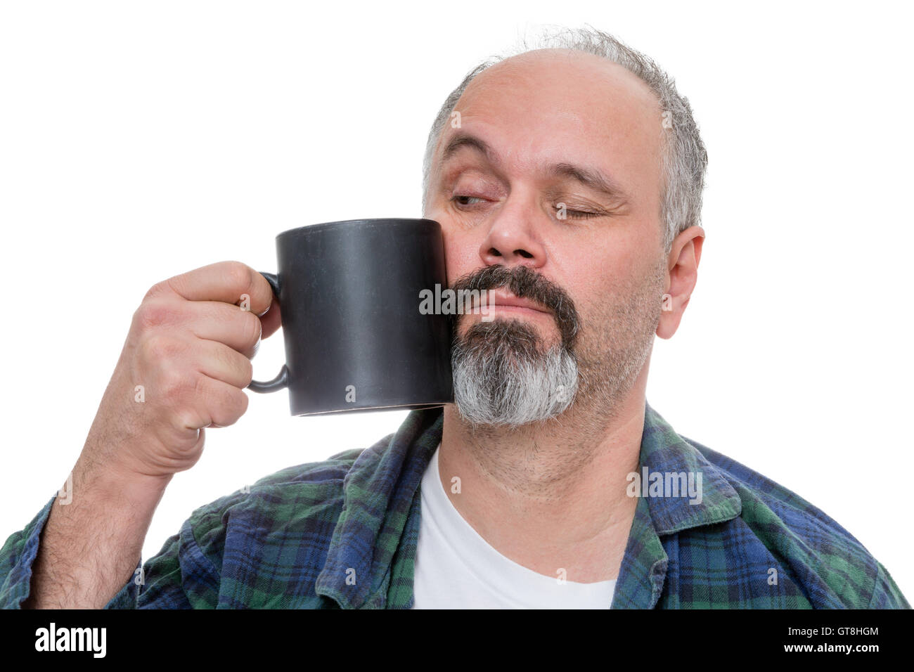 Riattiva uomo di mezza età vestito in flanella camicia e pigiami e ritirando la linea sottile con la barba tenta di bere da un caffè scuro m Foto Stock