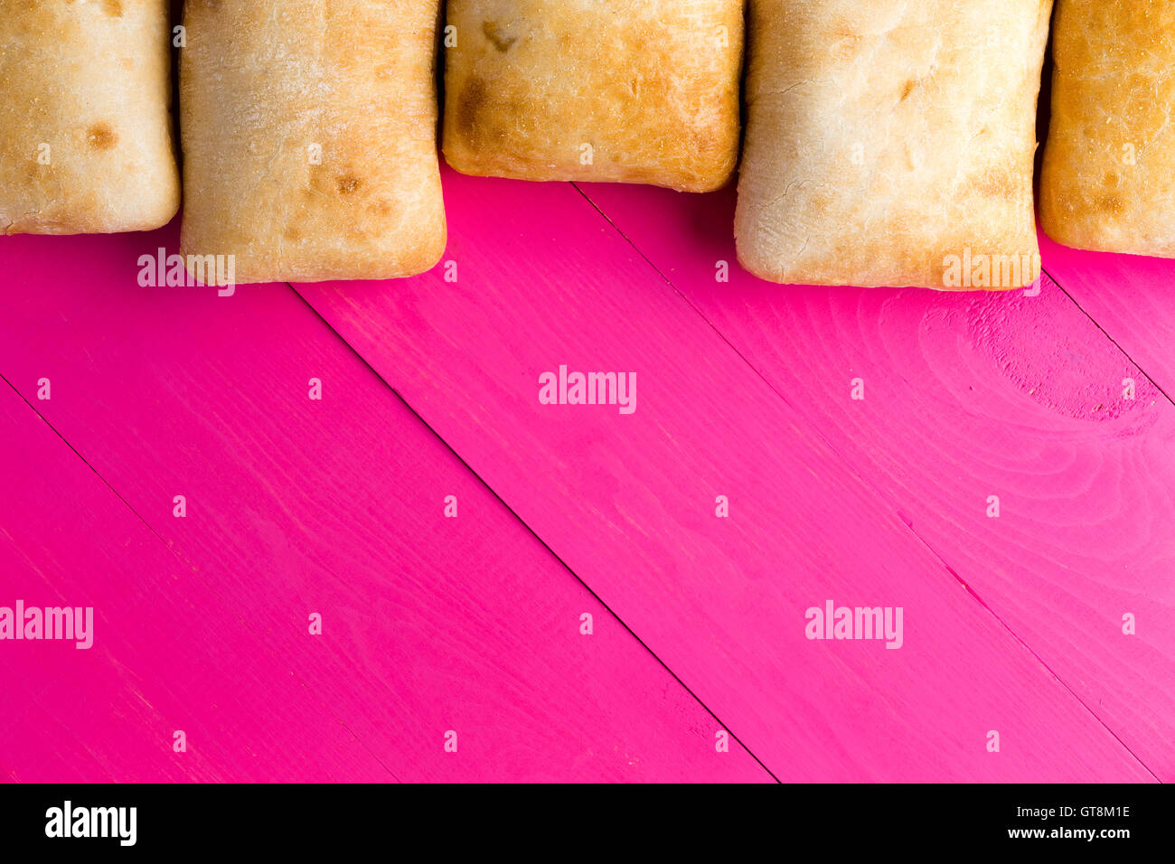 Confine di italiano ciabatta pane, una crosta di pane poroso realizzato con olio d'oliva, sul Rosa esotico di tavole di legno con copia spazio, overh Foto Stock