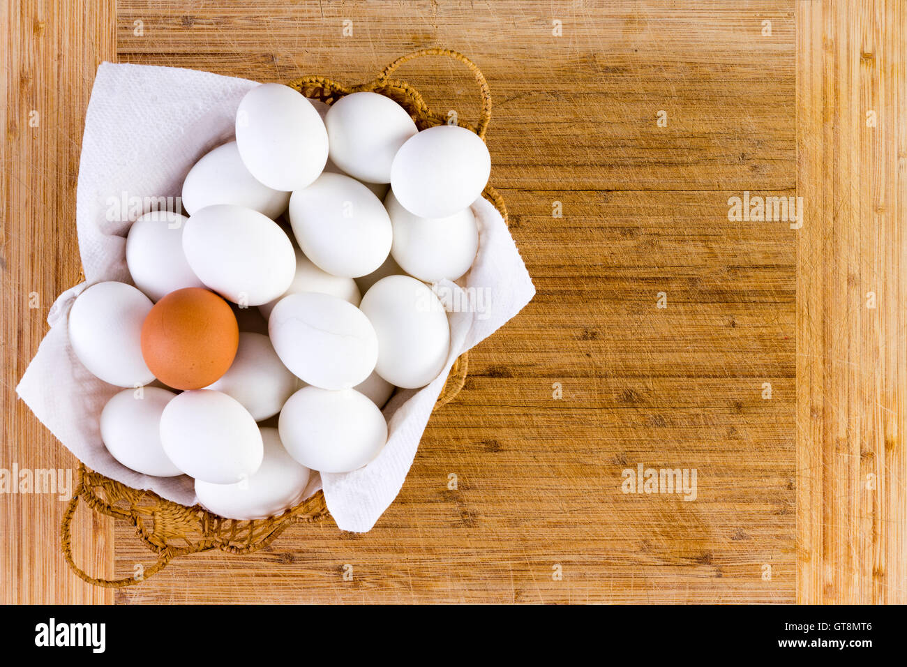 Unico riempito di vimini con singolo uovo marrone sulla parte superiore di quelli bianchi su un tavolo di legno con uno sfondo con spazio di copia Foto Stock