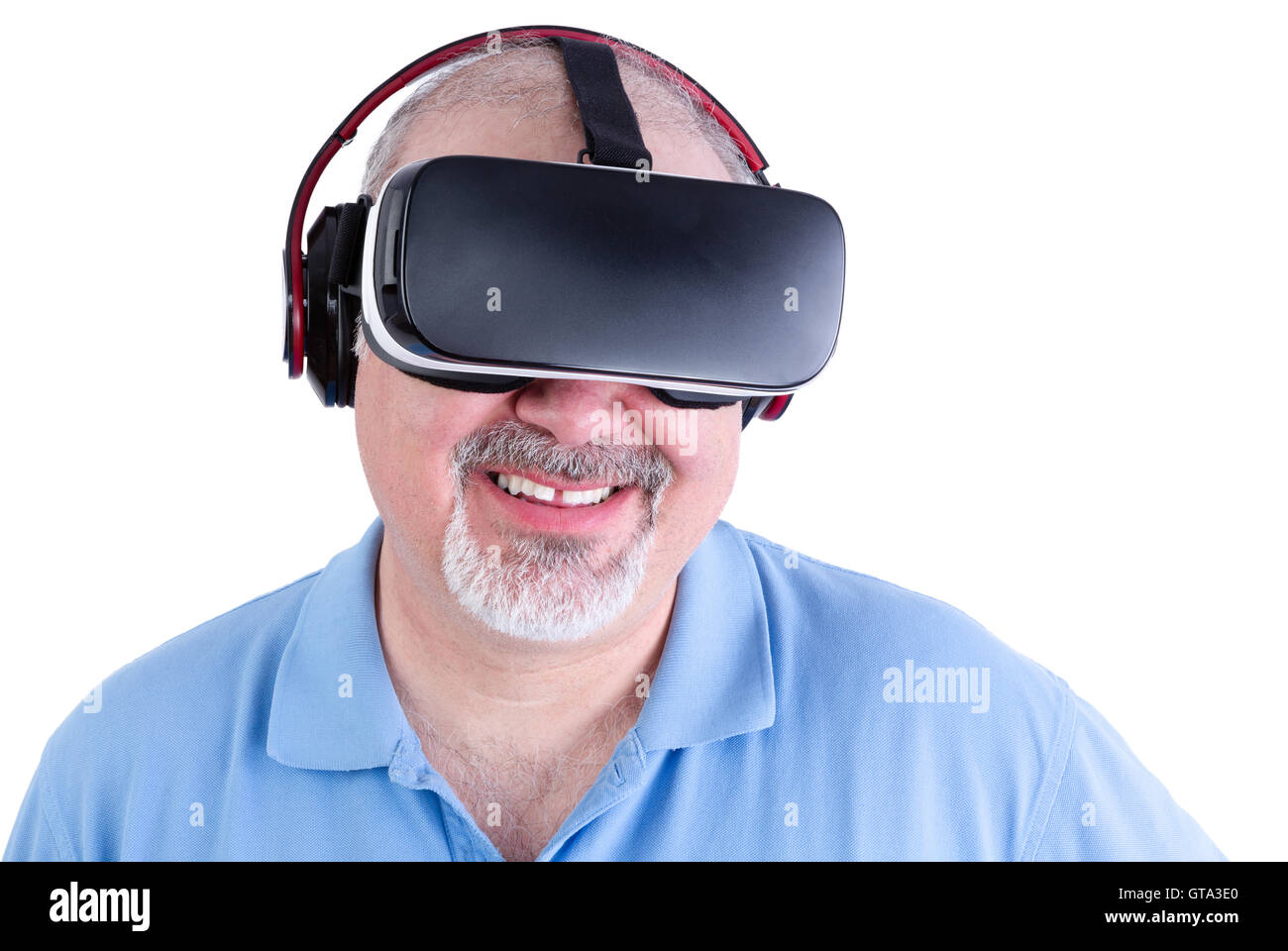 Unico barbuto uomo maturo in maglietta blu sorridente con la realtà virtuale auricolare su sfondo bianco Foto Stock