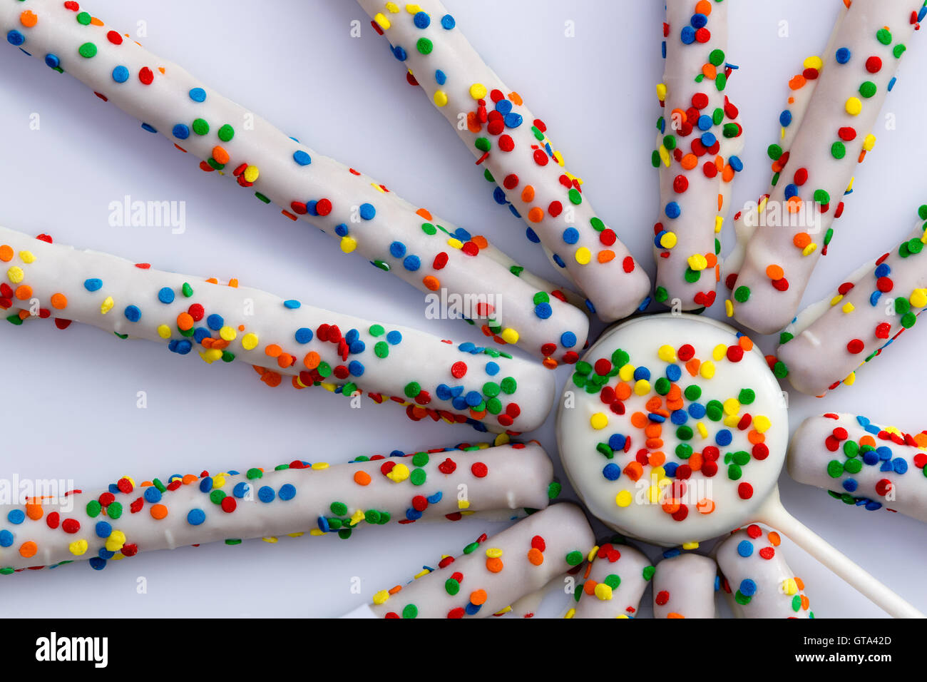 Parte superiore verso il basso vicino sul volante di forma rettilinea pretzel rivestito in cioccolato bianco e colorato di zuccherini Foto Stock