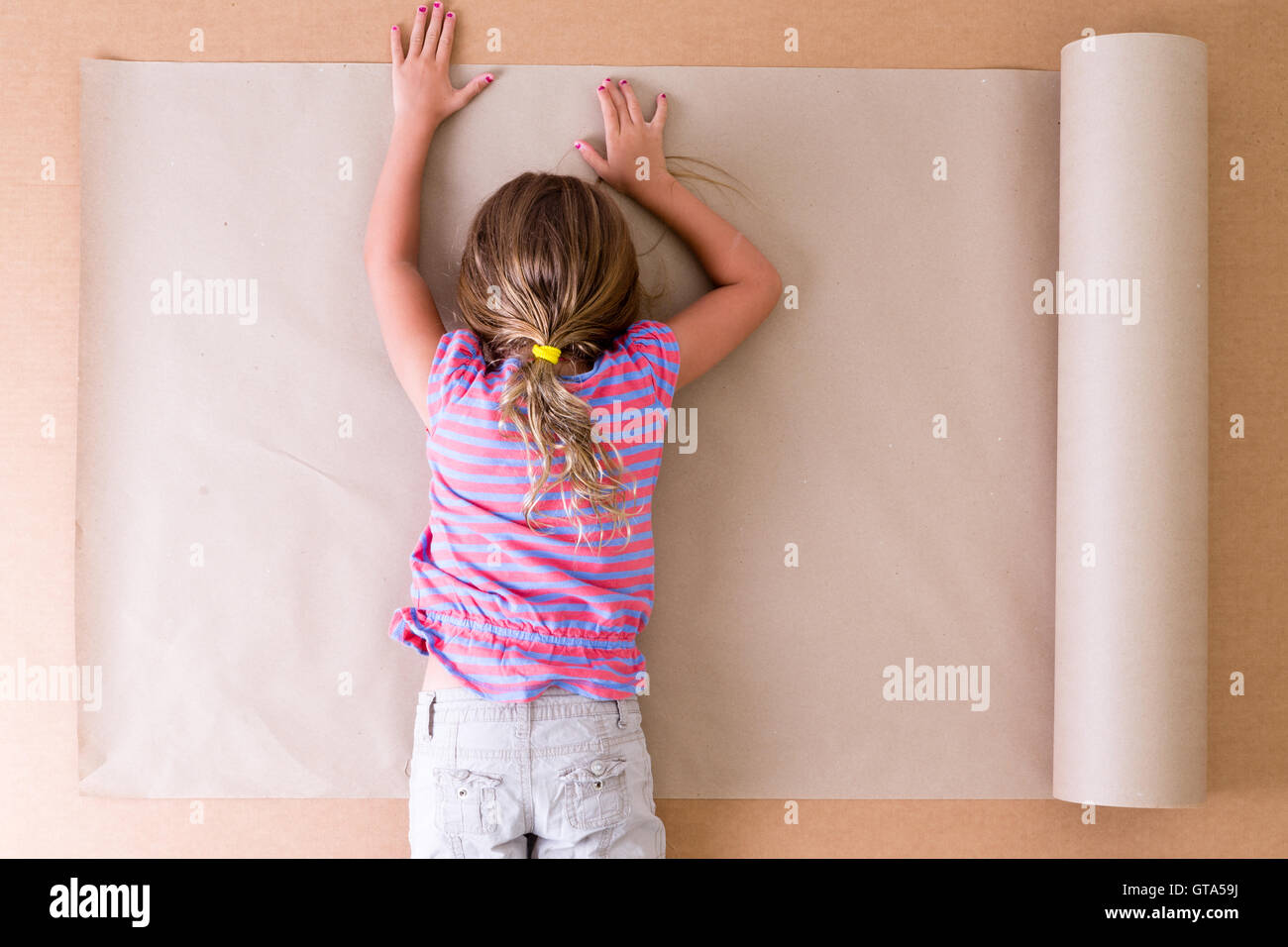 Premuto giovane bambina artista sdraiato a faccia in giù sulla carta come lei le lotte per venire con idee originali e creative des Foto Stock