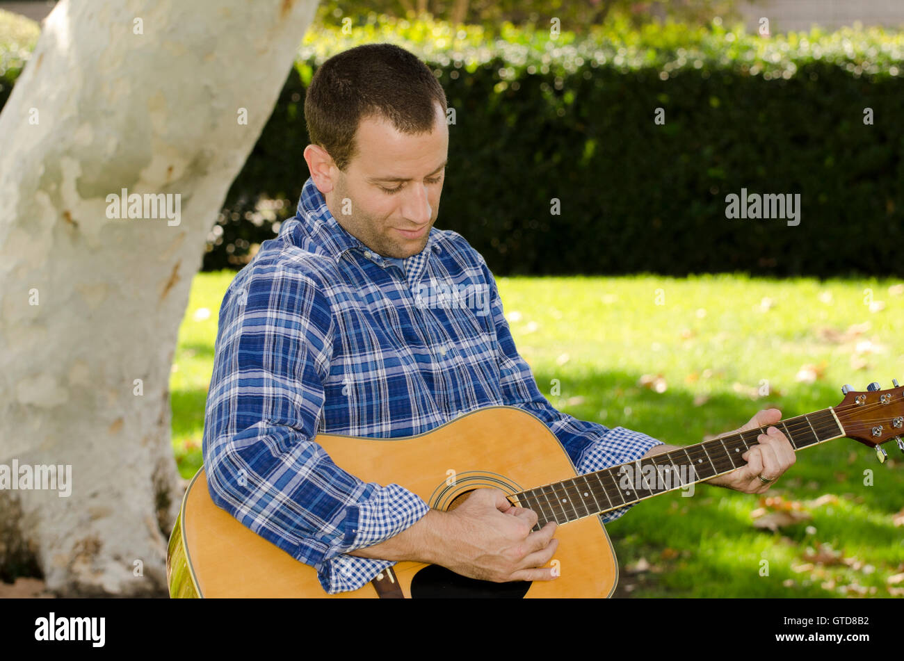 Creazione di musica - Uomo suonare la chitarra acustica nel parco. Foto Stock