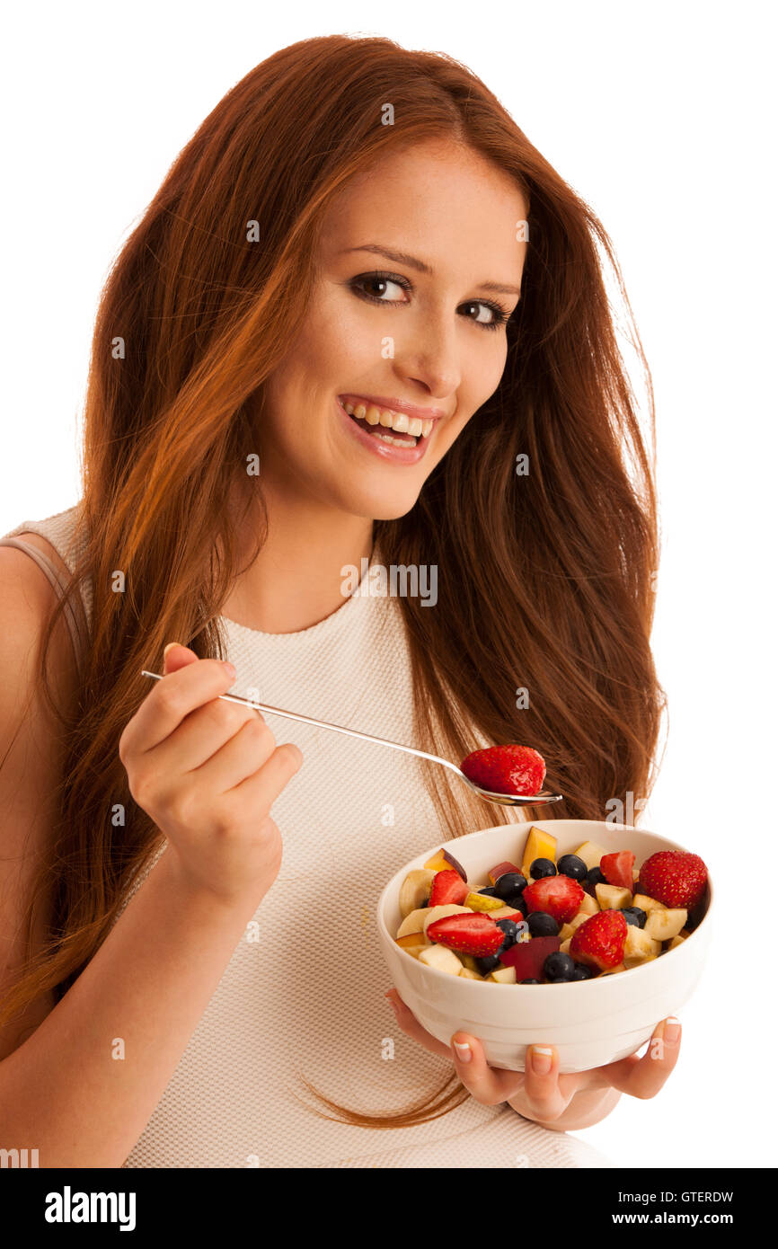 Mangiare sano - donna mangia una ciotola di insalata di frutta isolato su sfondo bianco - Pasto vegetariano Foto Stock