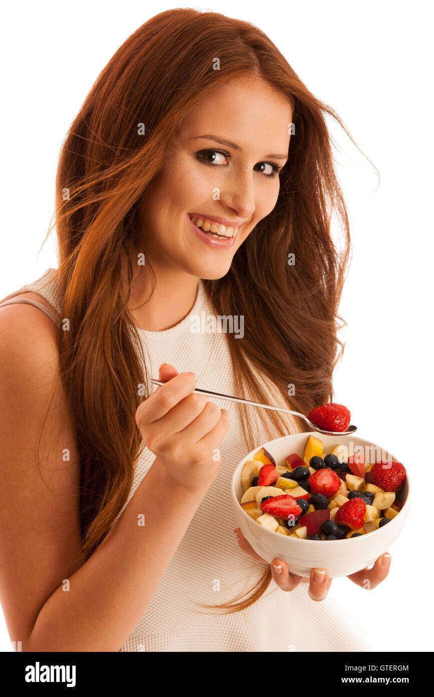 Mangiare sano - donna mangia una ciotola di insalata di frutta isolato su sfondo bianco - Pasto vegetariano Foto Stock